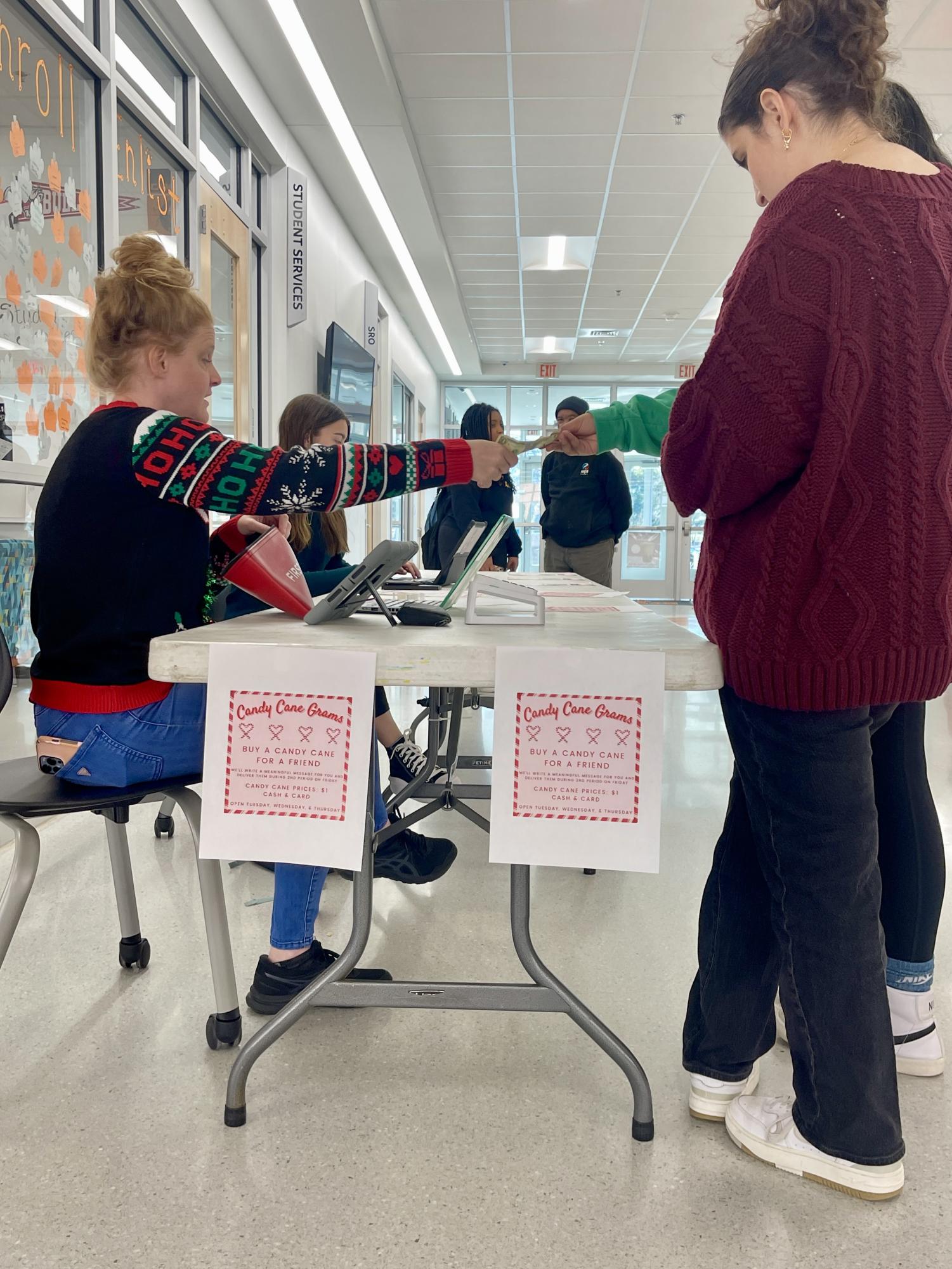 The student council has a table set up for both lunches, selling candy canes that will get passed on to their friends.