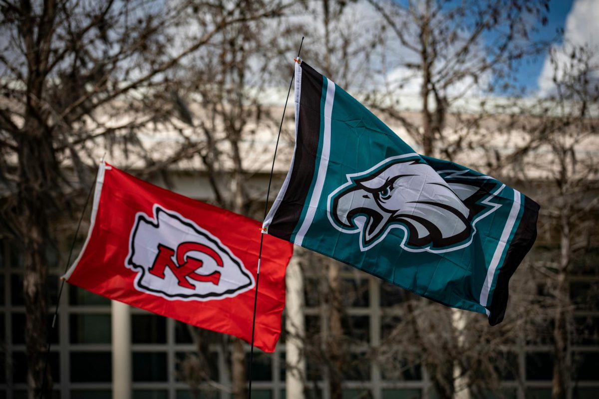 Flags of both teams fly in the wind at a building in New Orleans.

