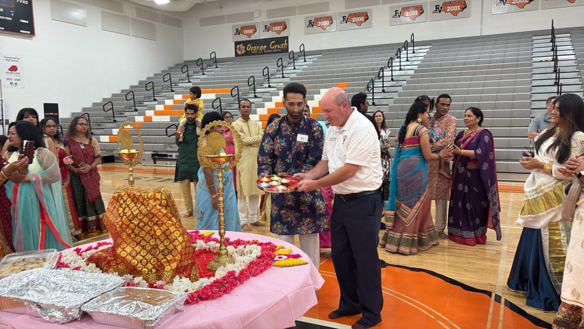A guest and an associate member participating in aarti at the Garba-Dandiya Night event.  